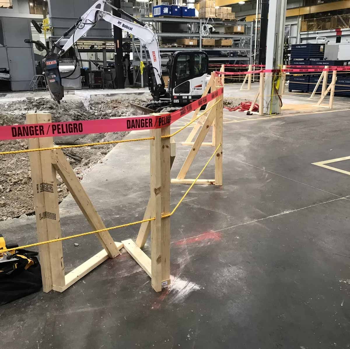 Excavator behind wooden barrier with red 