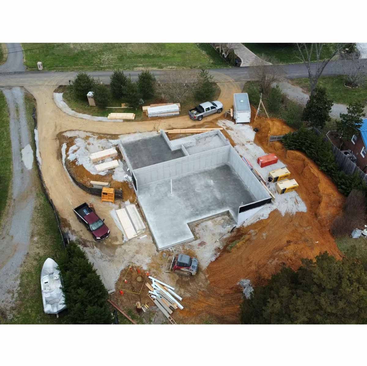 Aerial view of a construction site. Concrete foundation walls and dirt piles surround a new structure.
