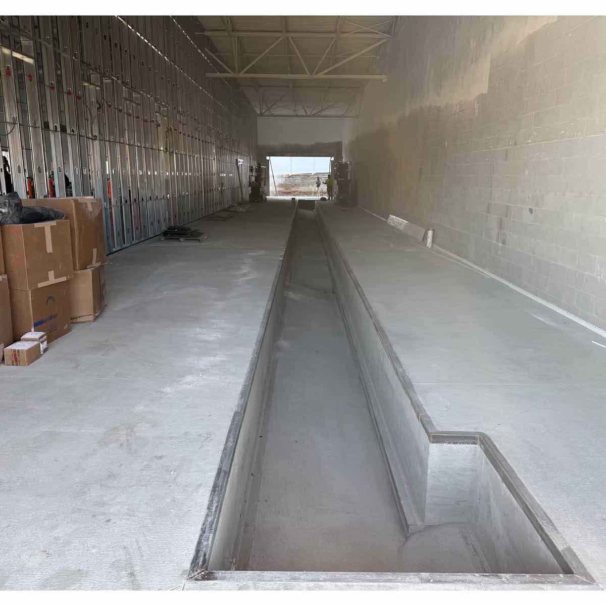 Concrete car wash bay under construction, with a long, recessed channel.