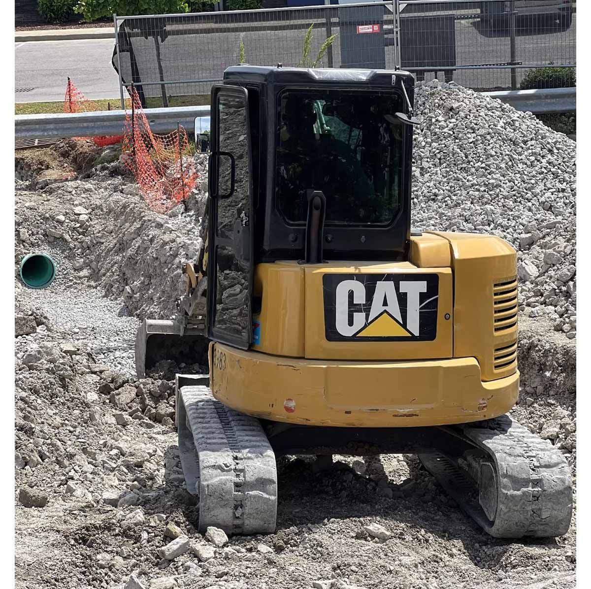 Yellow CAT mini excavator digging in a construction site.