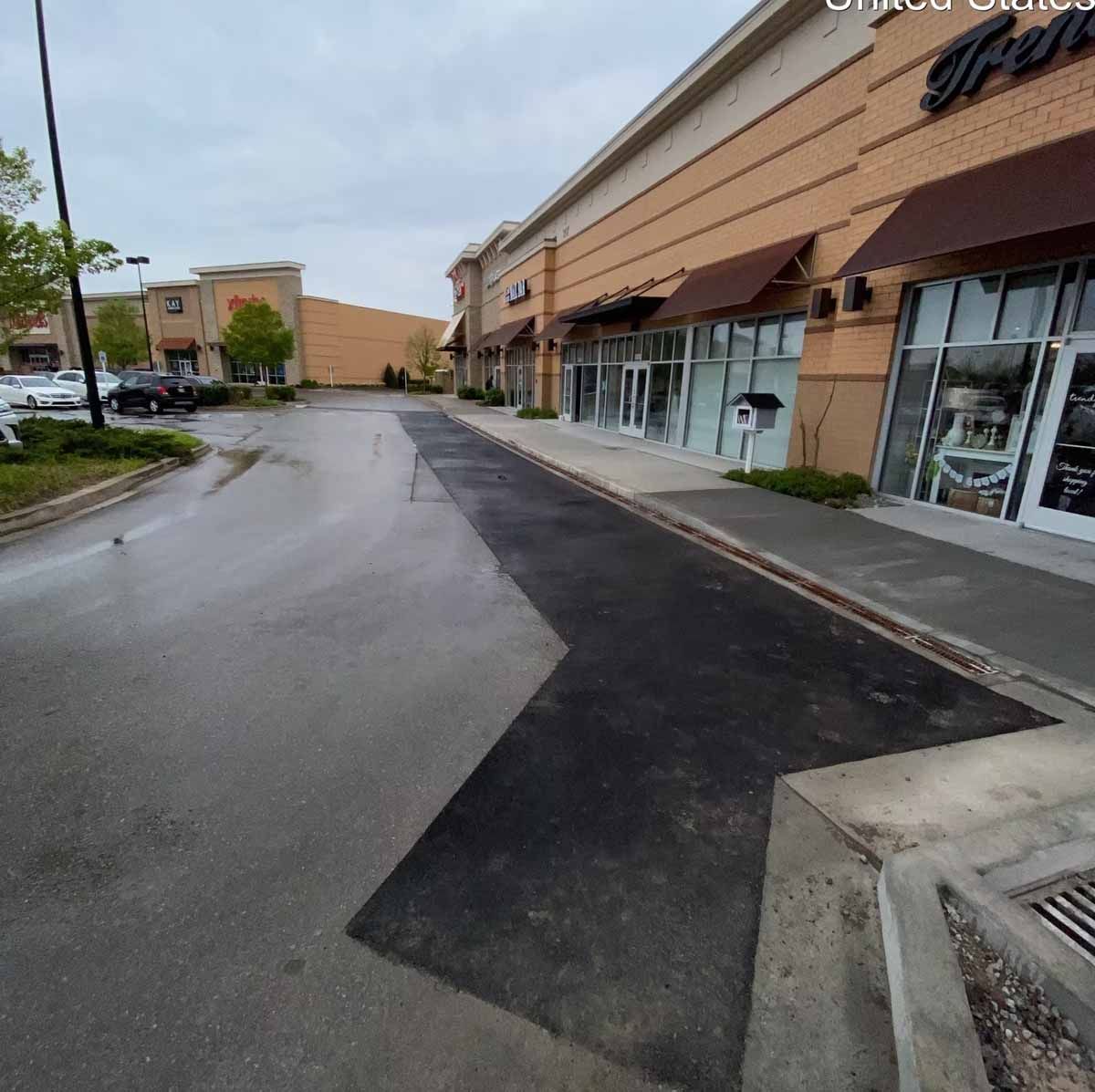 Exterior of a commercial building with a wet asphalt parking lot on a cloudy day.