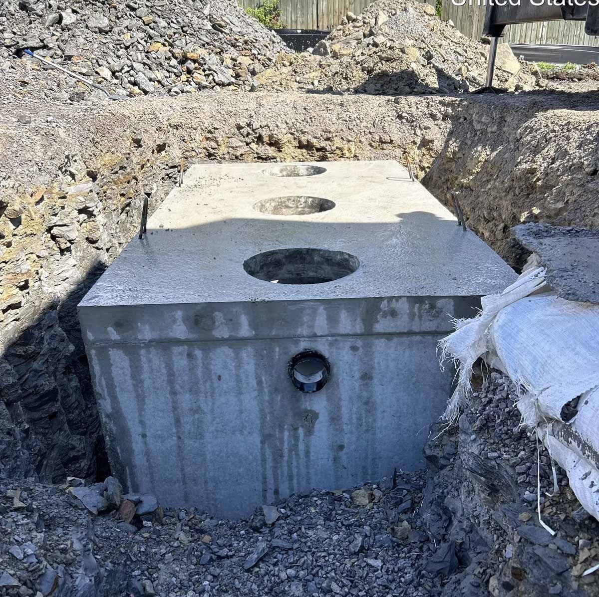 Concrete septic tank in a dug-out pit, ready for installation.