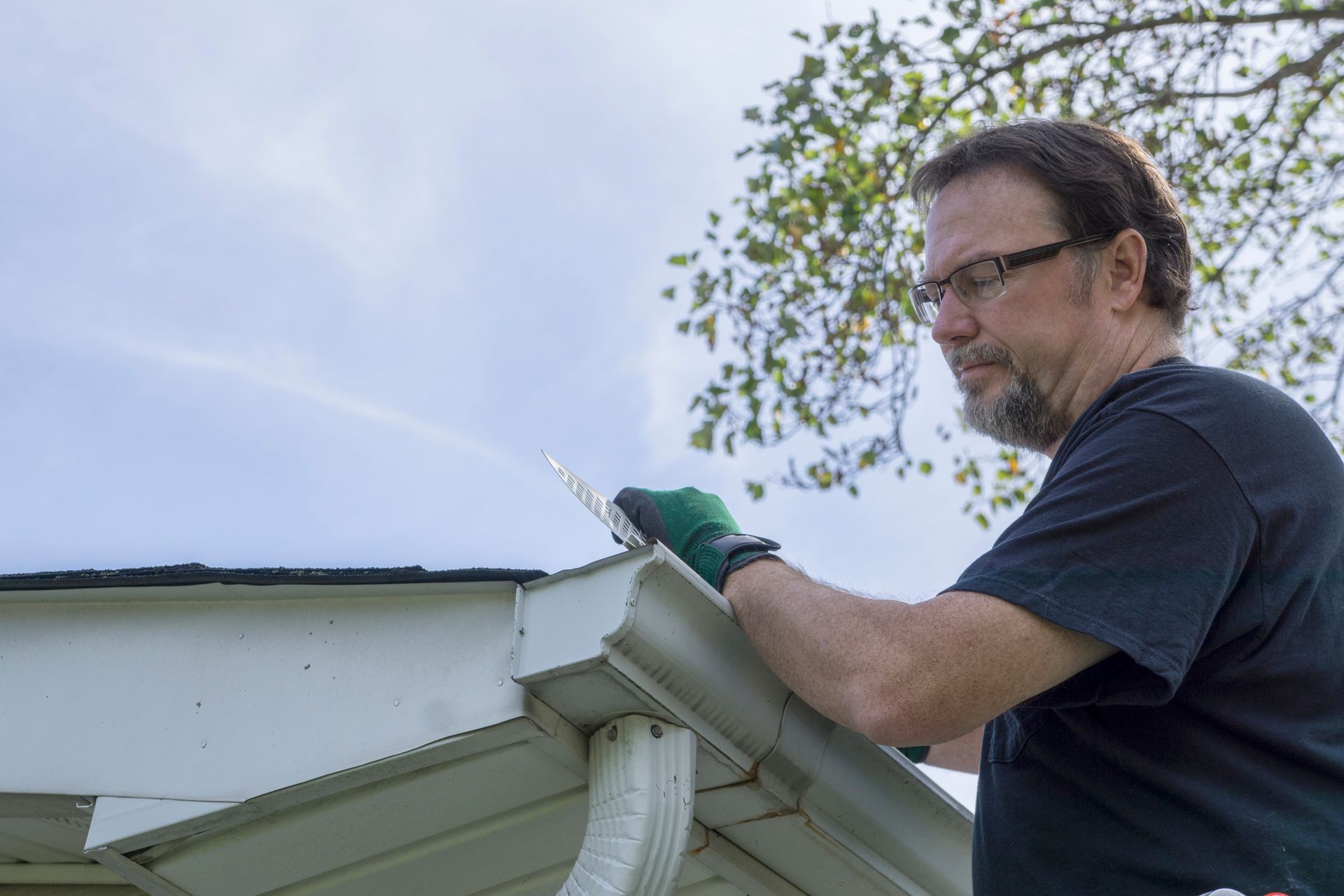 A person wearing glasses working on a roof | Gutter Guards Gregory Hills NSW | RSA Gutter Mesh
