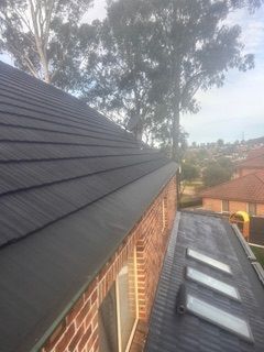 A brick house with a black roof and skylights on the roof.