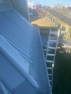 A ladder is sitting on top of a roof next to a gutter.