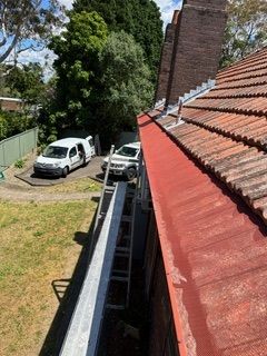 A white van is parked on the side of a building next to a gutter.