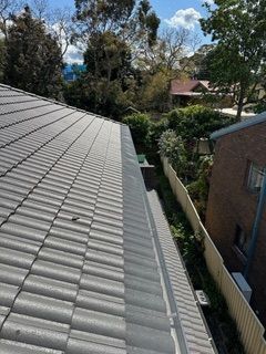 A roof with a gutter on it and a fence in the background.