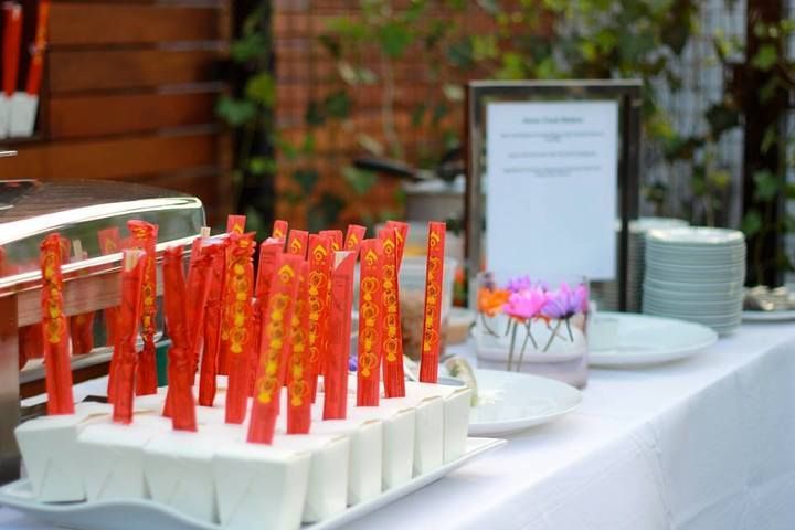 Table setting with red and gold food sticks in white containers, plates, and a sign.