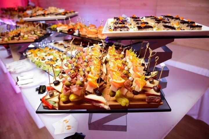 A buffet table filled with lots of food and people standing around it.