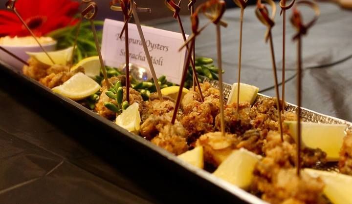 Fried oysters with lemon wedges and skewers on a platter.
