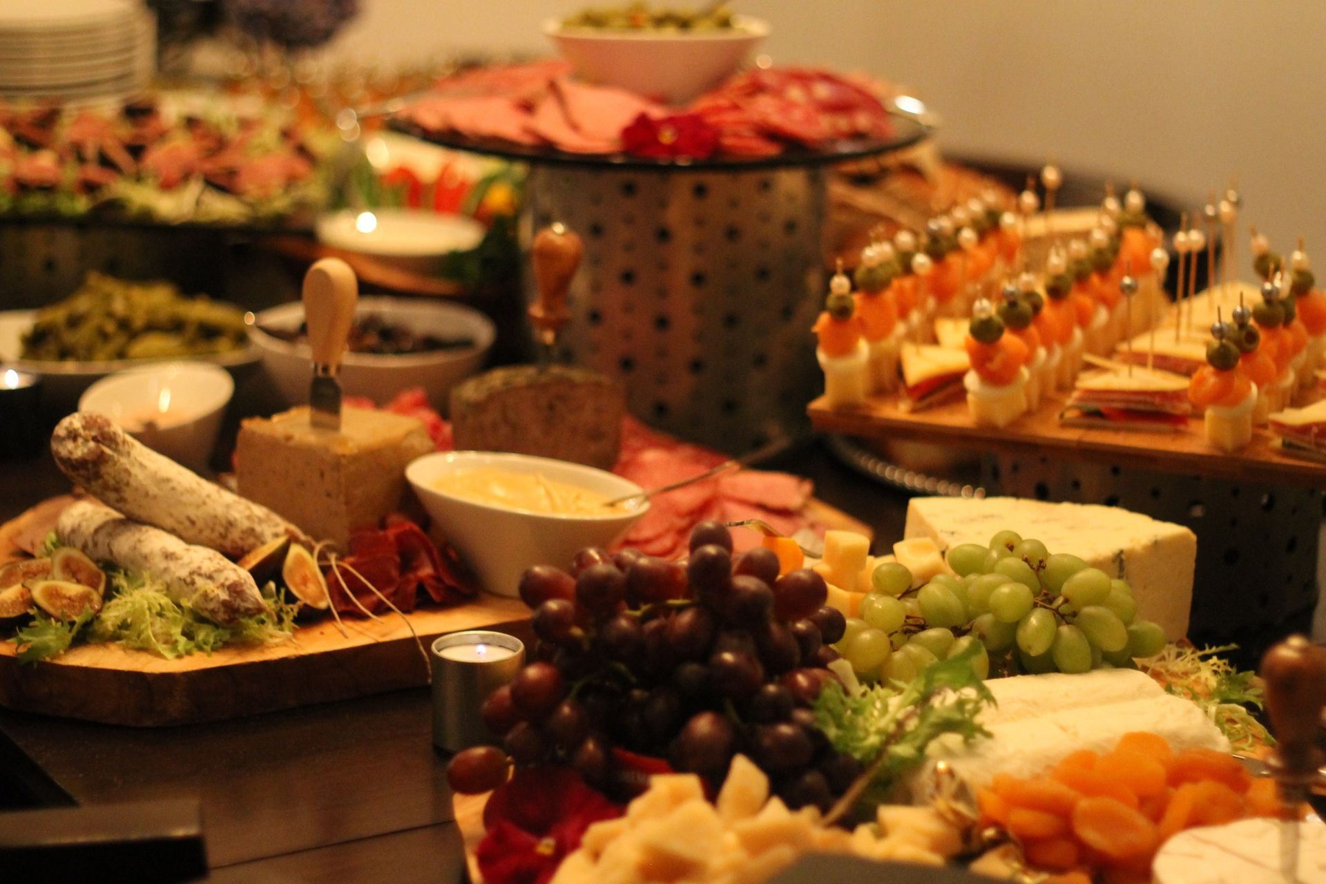 Charcuterie spread: cheeses, meats, grapes, olives, and appetizers on a table, catering setup.