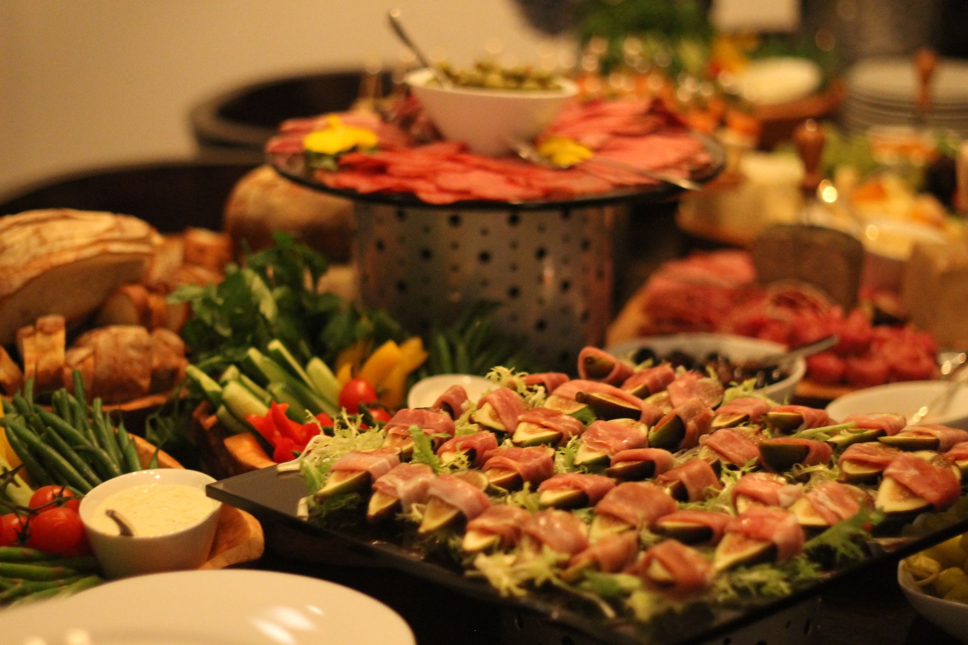 A person is holding a tong over a tray of meat.