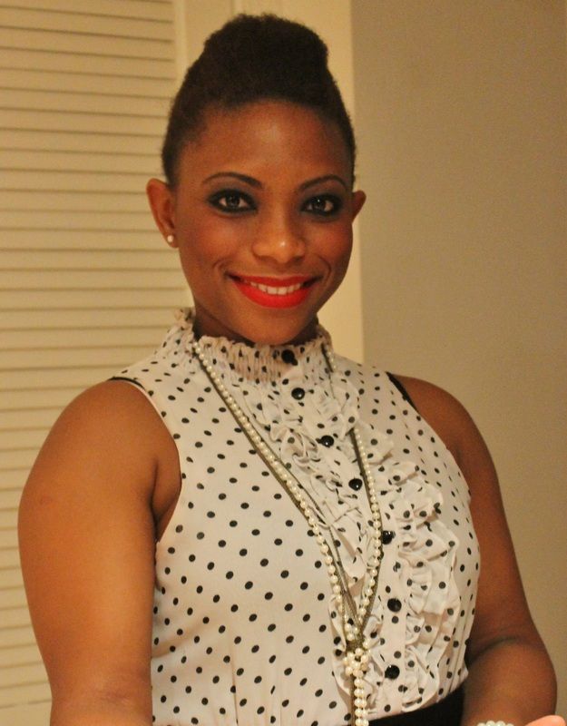 Woman smiling, wearing a polka-dot top, necklace, and red lipstick.