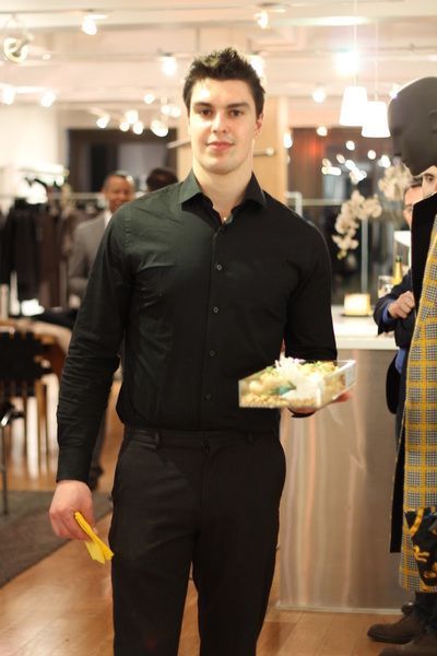 Man in black shirt and pants holding a gift box in a store setting.
