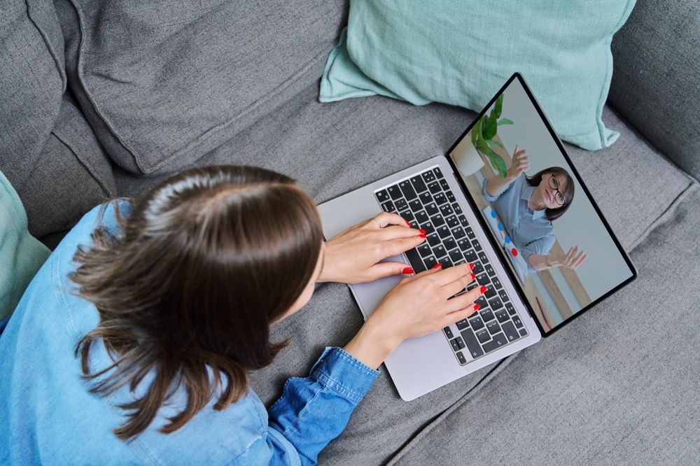 Person on a couch using laptop, video chatting with another person.