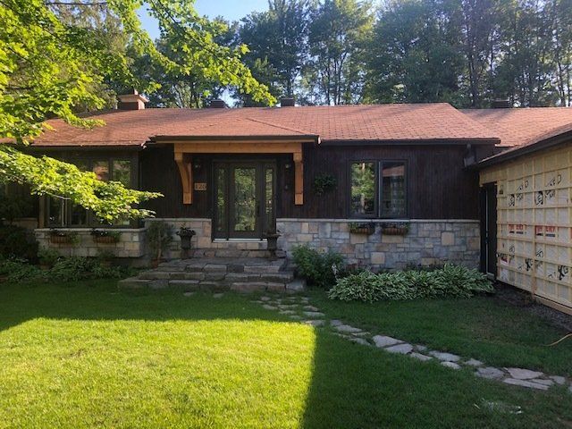 Une grande maison avec un toit rouge et une grande pelouse devant.