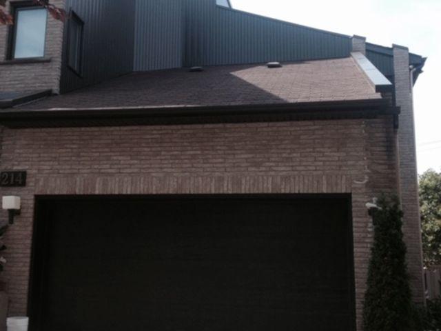 Une maison en brique avec une porte de garage noire et un toit