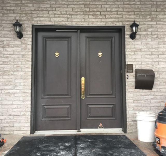 Un mur de briques avec une porte noire et une boîte aux lettres