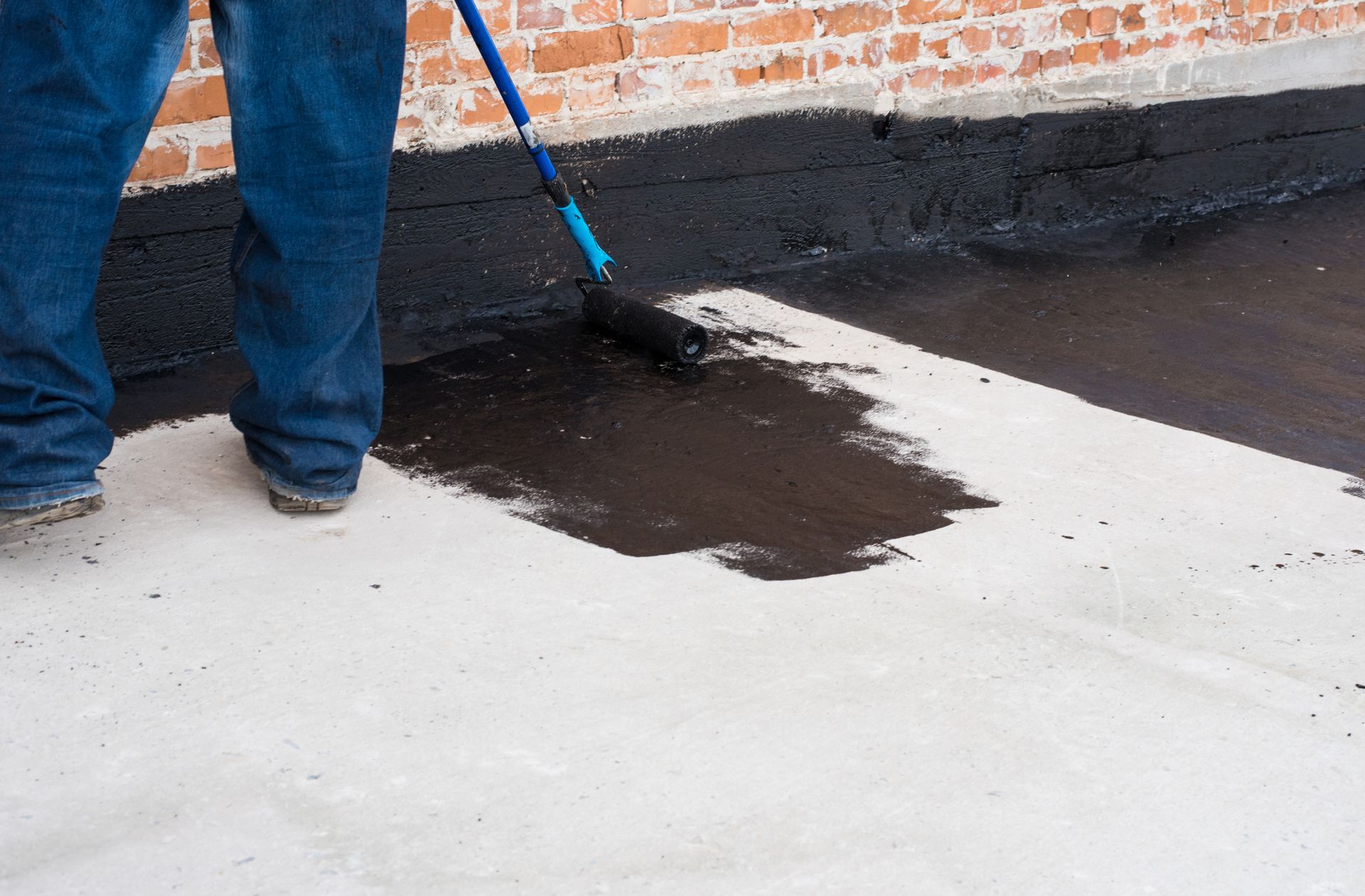 A worker from Flat Roofing Experts is applying roof coatings in South Valley, NM, to enhance roof pr