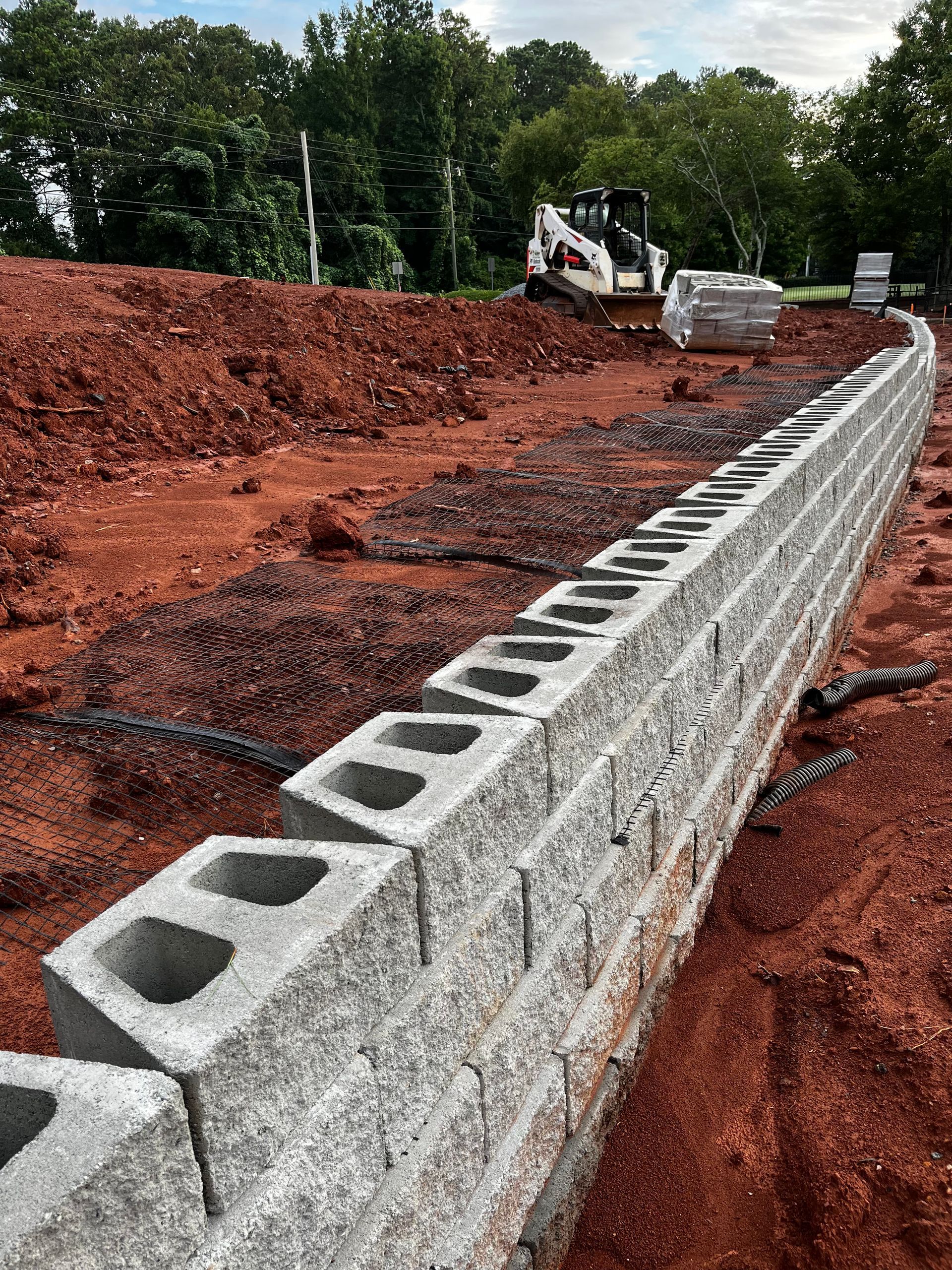 a concrete wall is being built in a dirt field with a bulldozer in the background .