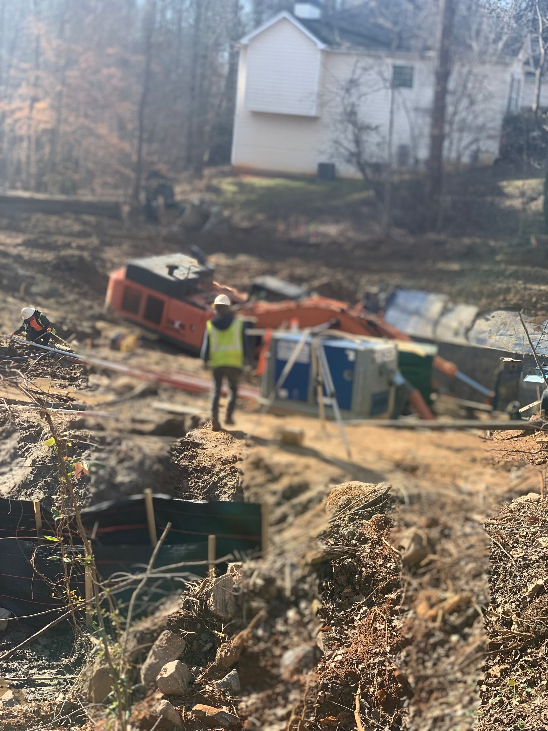 a man in a yellow vest is walking on a dirt road in front of a house .