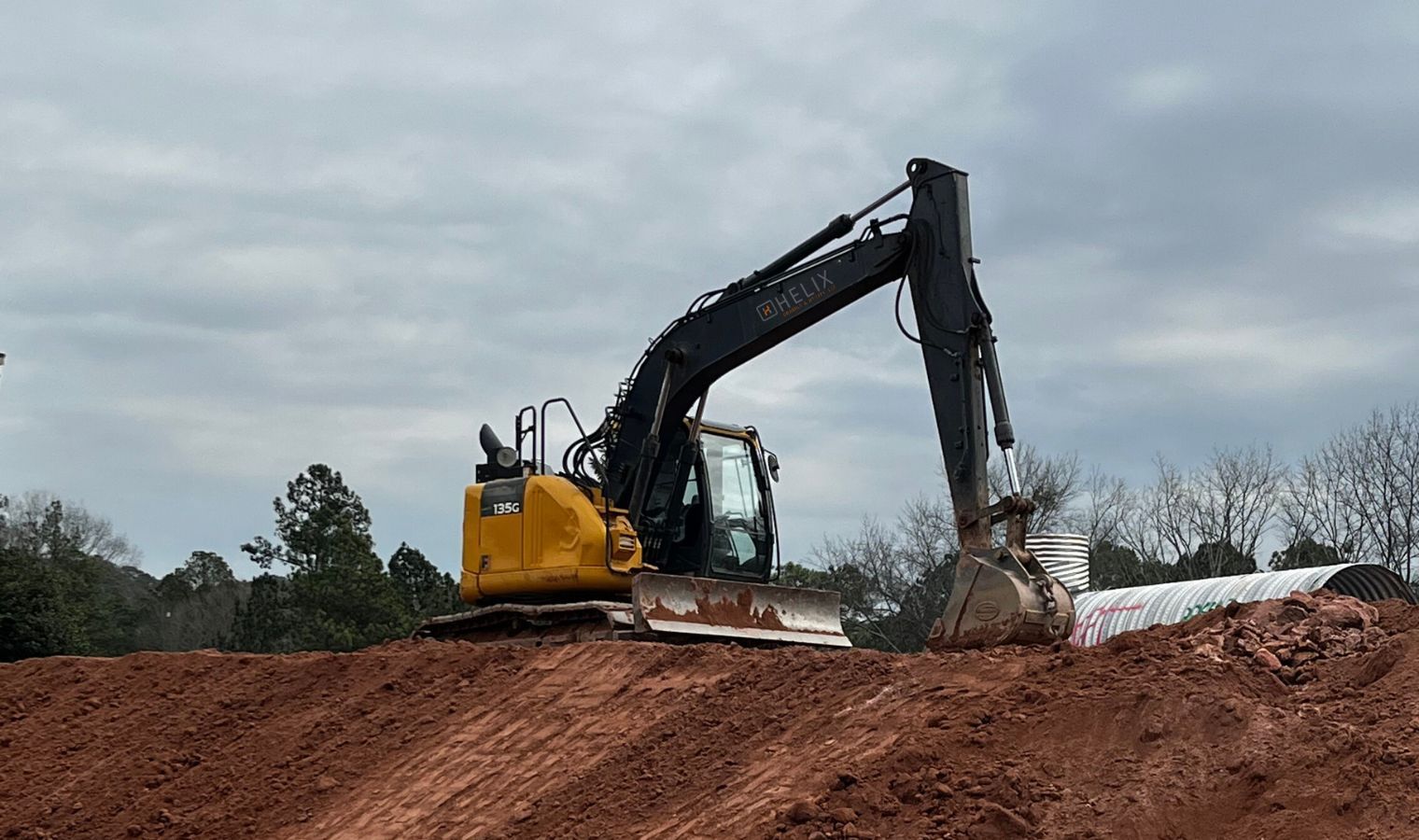 a yellow excavator is moving dirt on a hill .