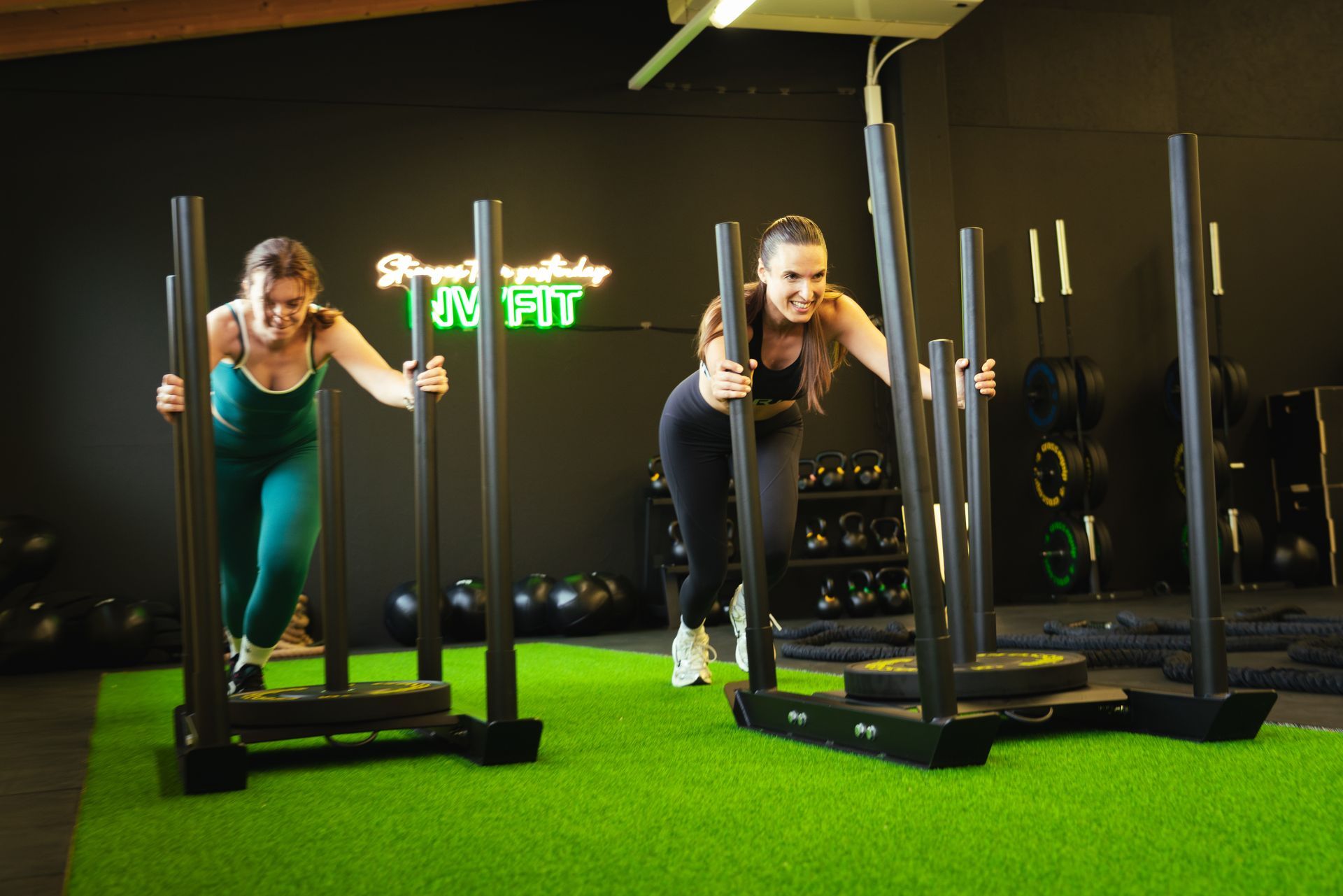 Close-up of black gym weight plates and a bench in a dimly lit fitness room