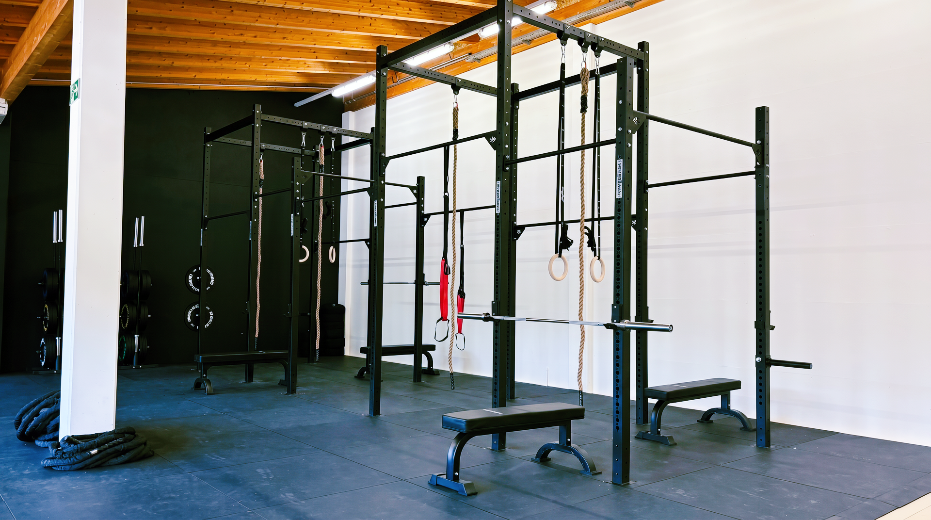 Modern gym interior with cable machines, mirrors, and dumbbells under orange accent lighting