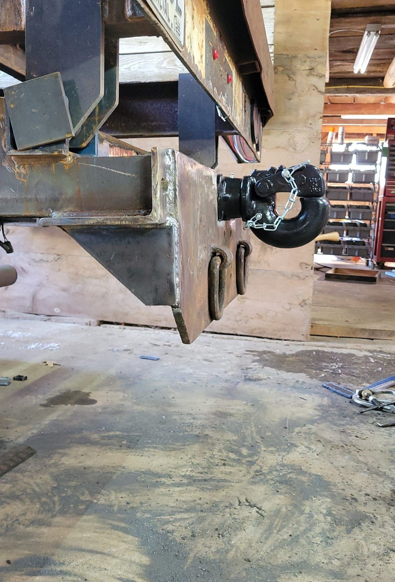 A metal hook is attached to a trailer in a garage.