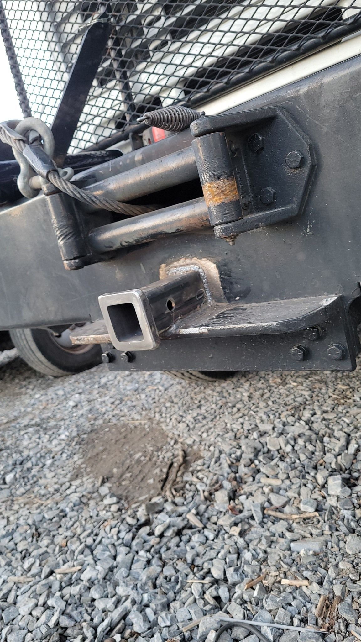 A close up of a truck 's bumper on a gravel road.