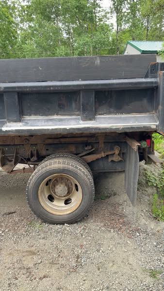 A dump truck is parked on a gravel road.