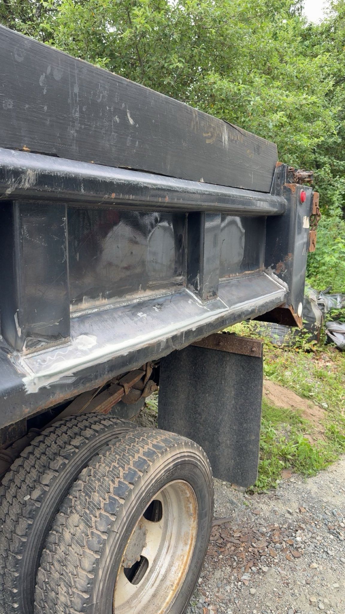 A black dump truck is parked on a gravel road.