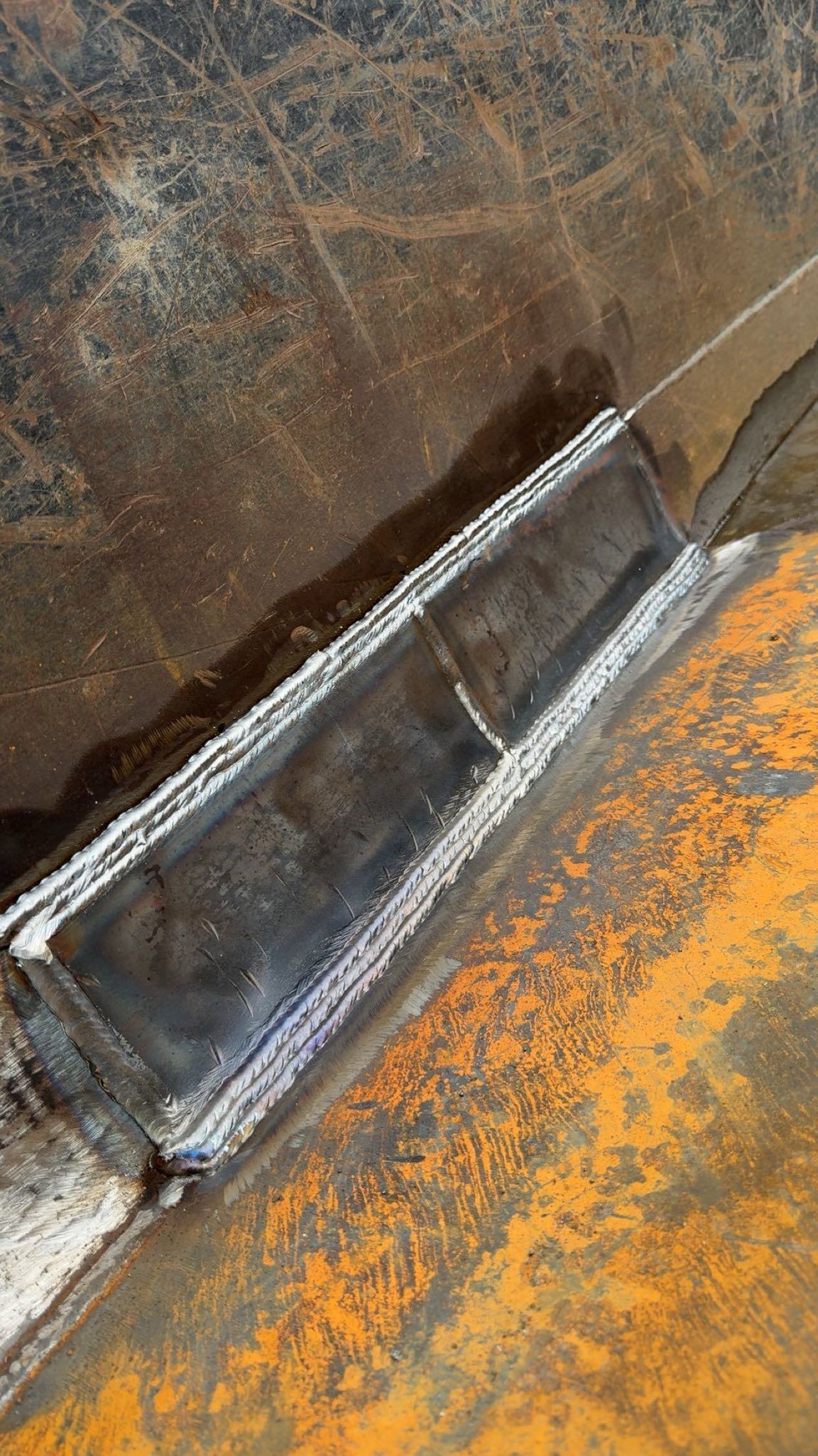 A close up of a piece of metal on a rusty surface.