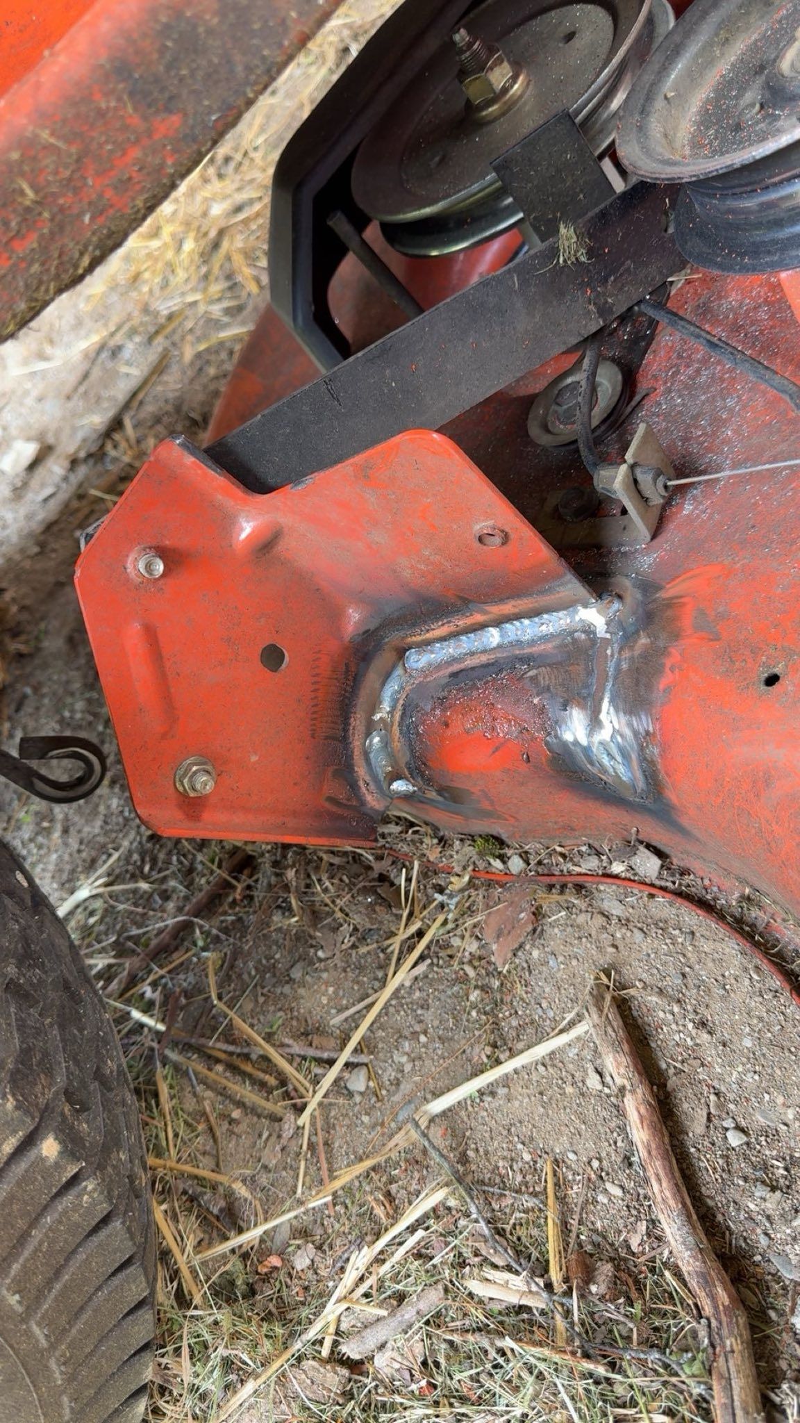 A red piece of metal is sitting on the ground next to a tire.