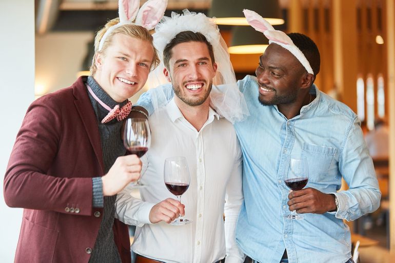 Three people in bunny ears toast with wine glasses at a festive indoor party