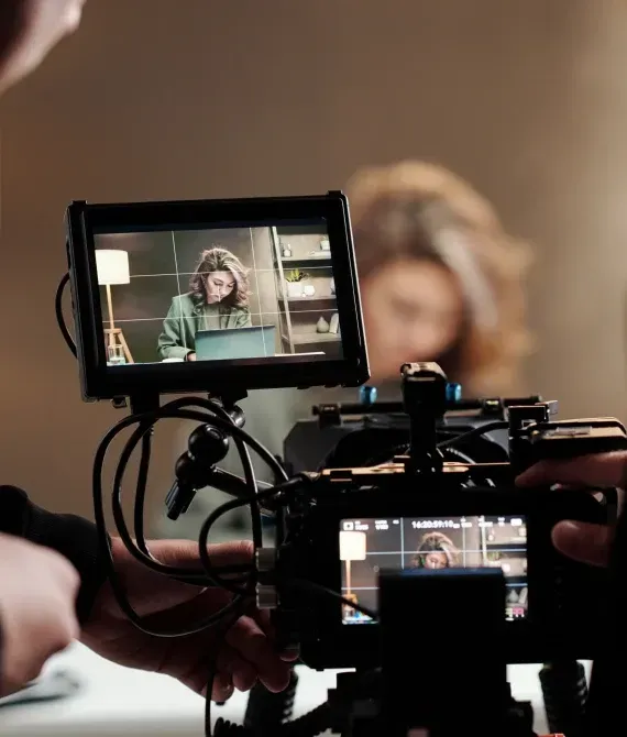Camera filming a person on a monitor in a studio setting