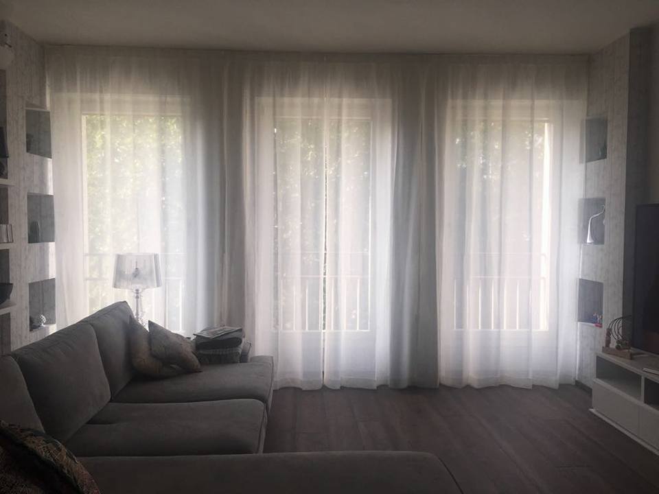 Un soggiorno con un divano, tende e una televisione.