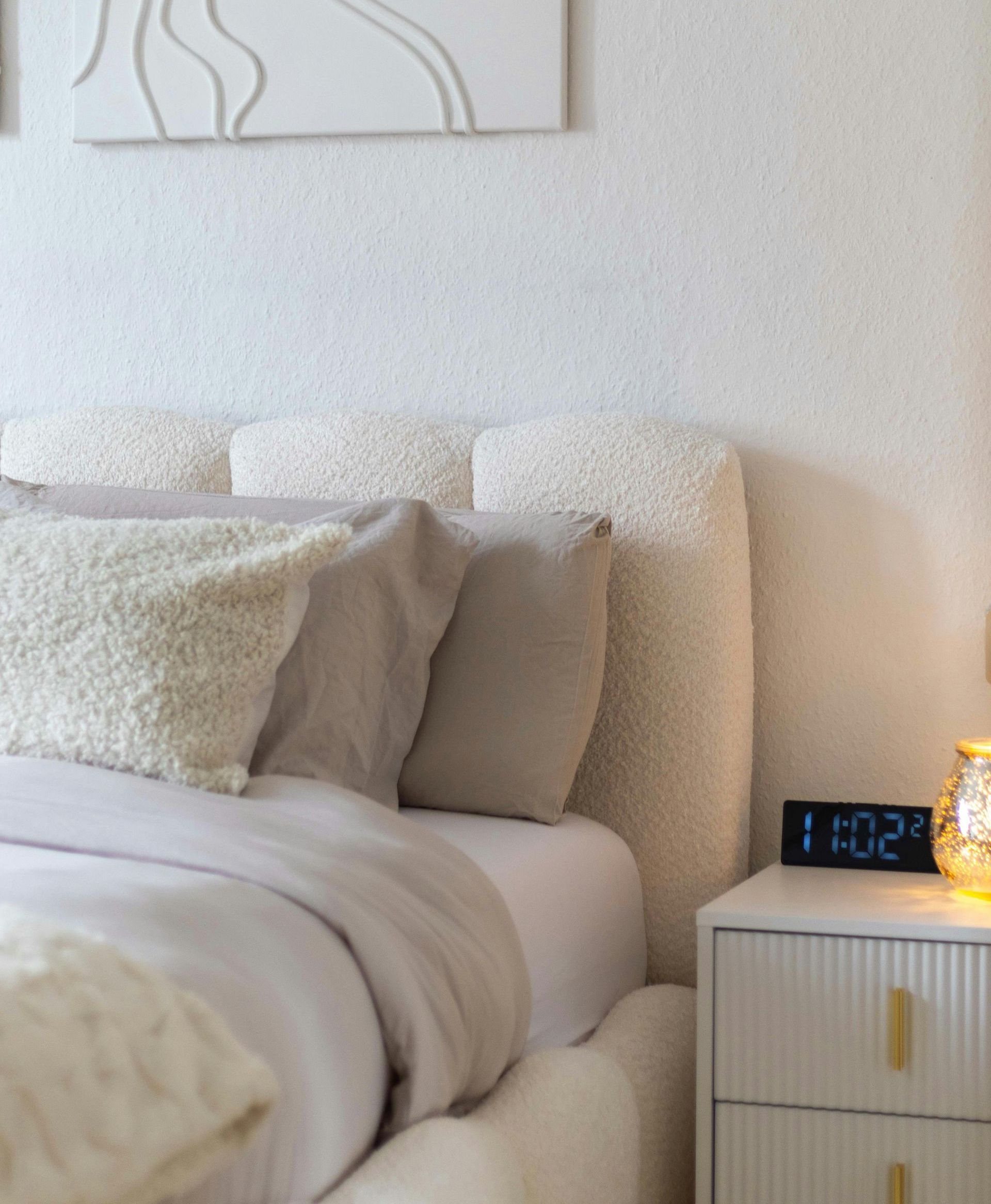 Una camera da letto con un letto e un orologio che segna 1:02