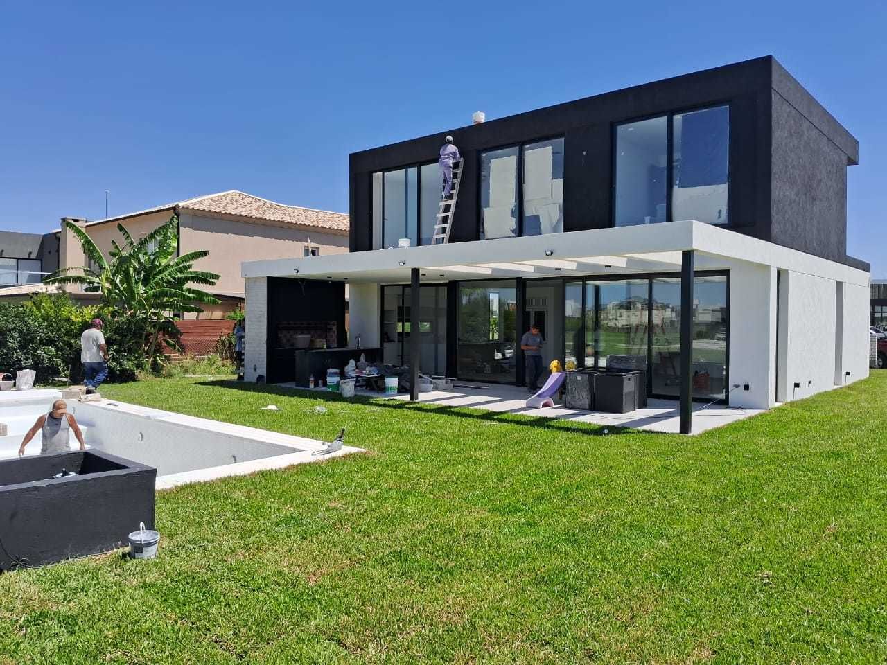 Casa moderna de dos plantas con planta superior negra y planta baja blanca, amplios ventanales