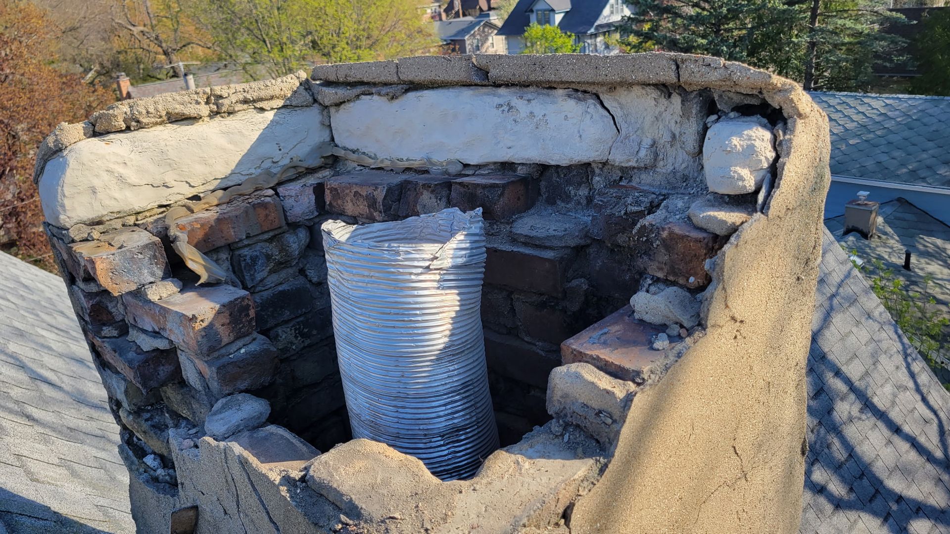 A brick chimney with a hose coming out of it.