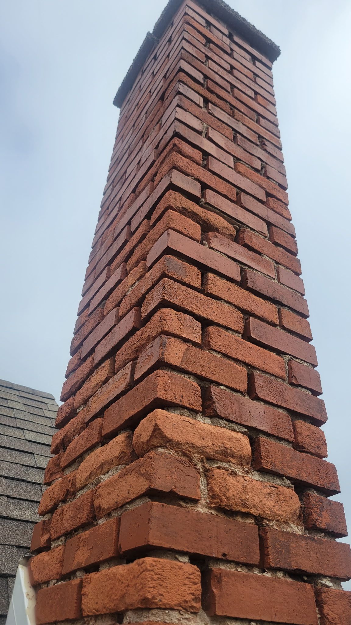 A tall brick chimney is sitting on top of a roof.