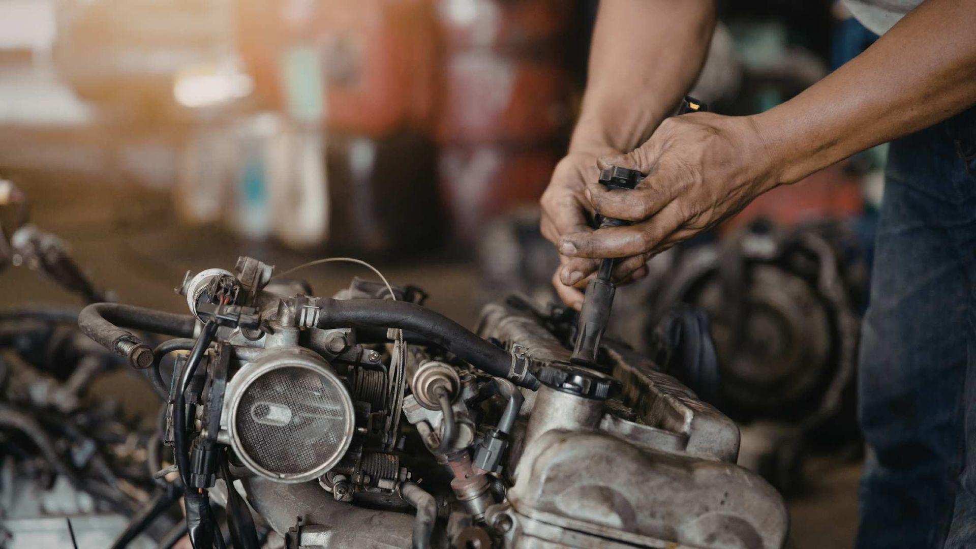 Mechanic tightening bolts on a motorcycle engine in a workshop