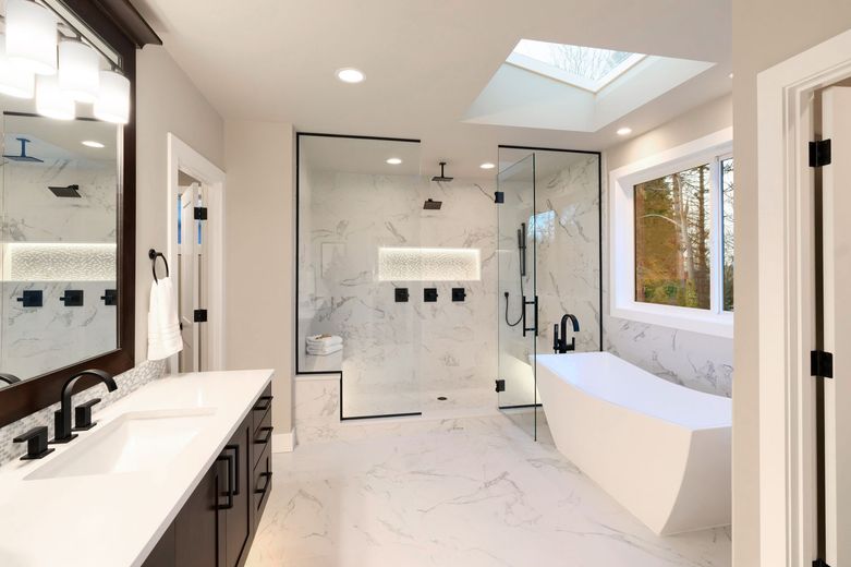 A bathroom with two sinks , a tub , a shower and a skylight.