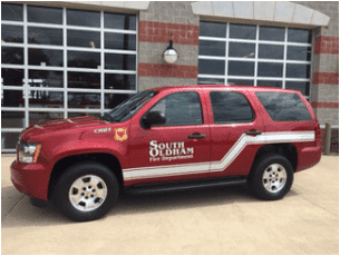 A red suv is parked in front of a building that says south oldham