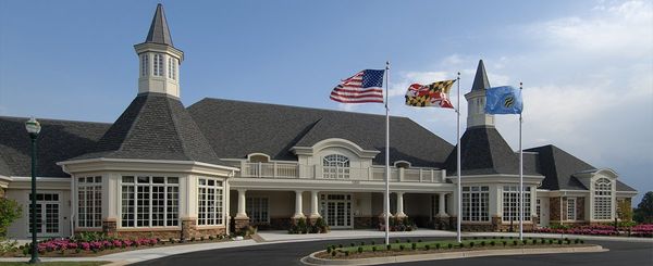 A large building with a dark roof and three flags waving in the breeze.