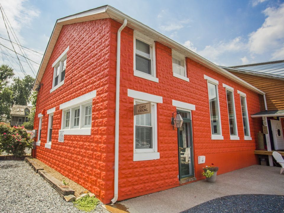 Red building with white trim, several windows, and a black door.