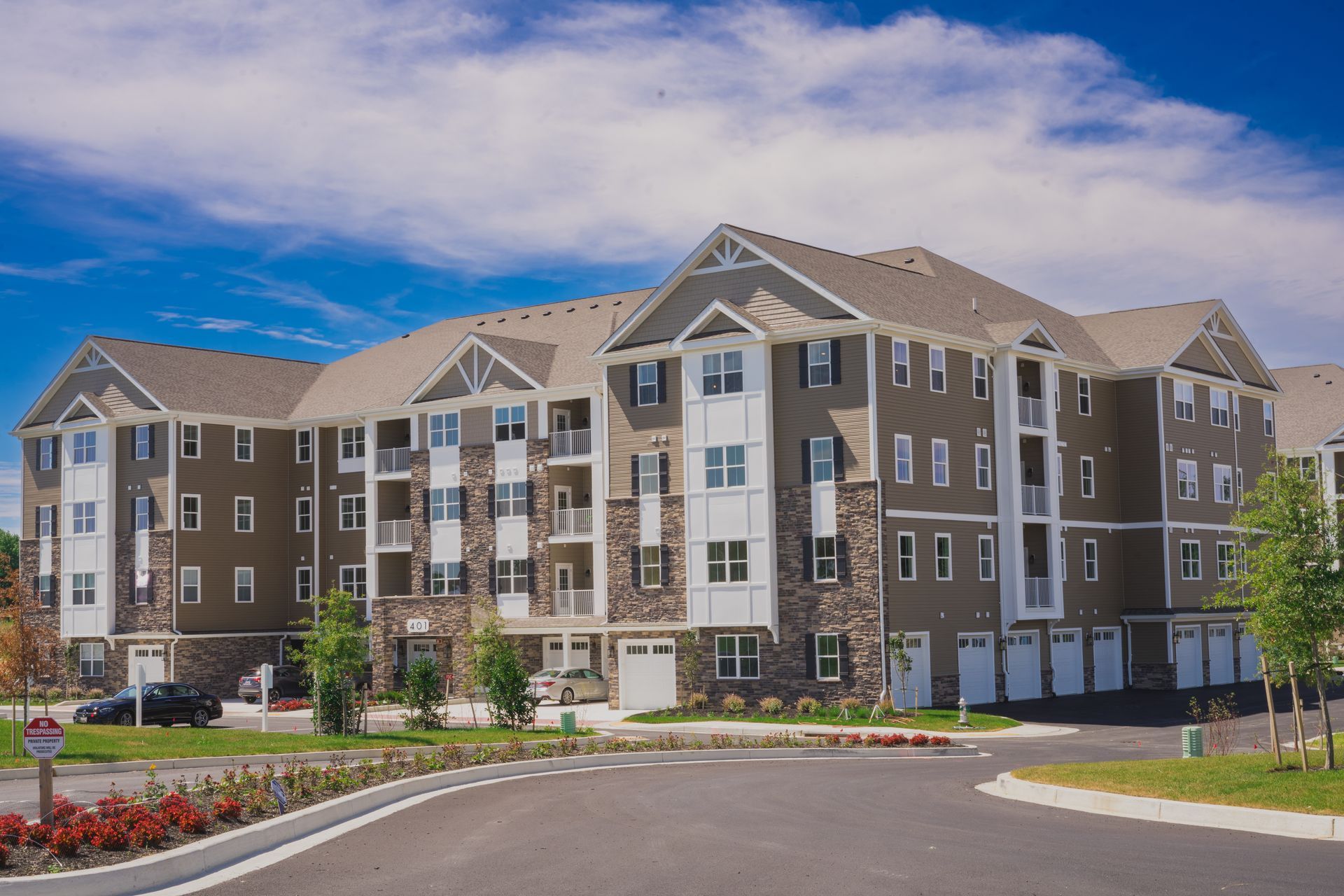 Multi-story apartment building with tan siding, stone accents, and a circular driveway.