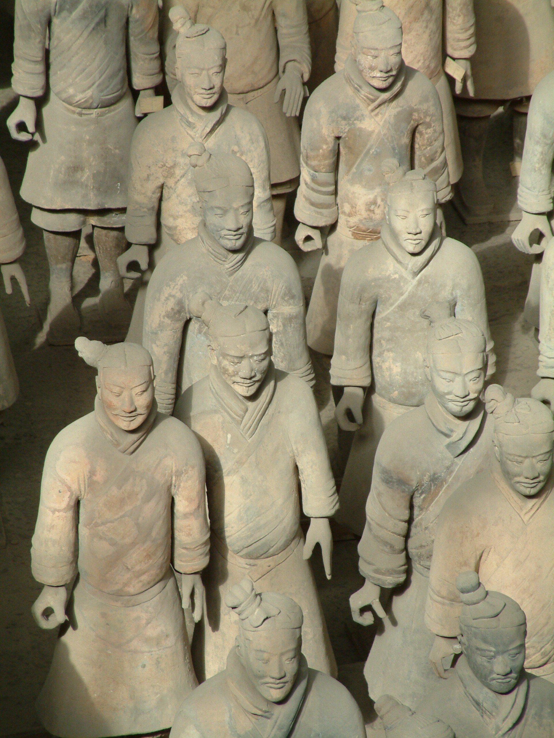 Terracotta krijgers staan ​​in formatie, gekleed in traditionele wapenrusting en met vastberaden uitdrukkingen op hun gezicht.