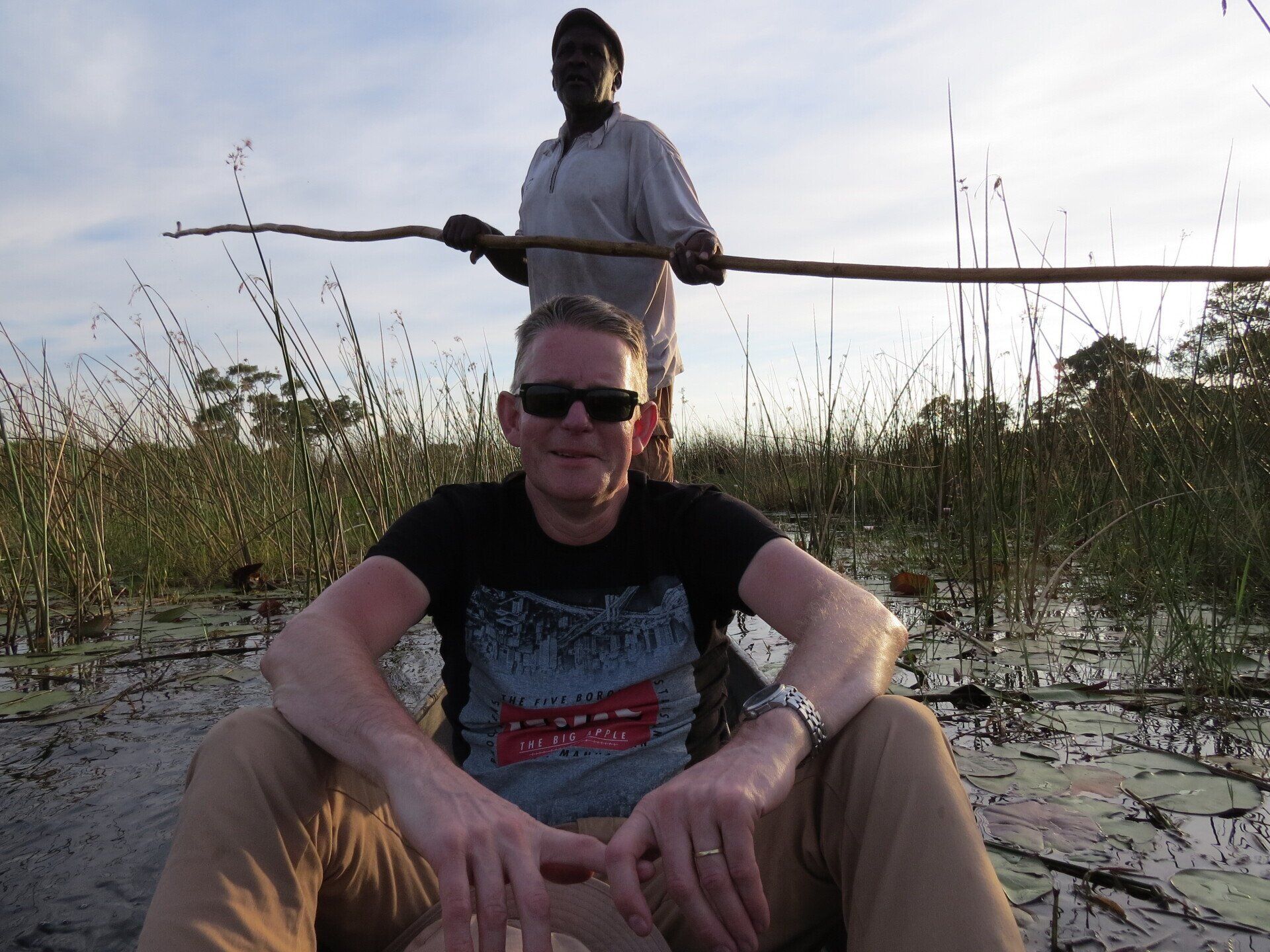 Man in een boot met een inheemse gids die een stok vasthoudt in het moeras.
