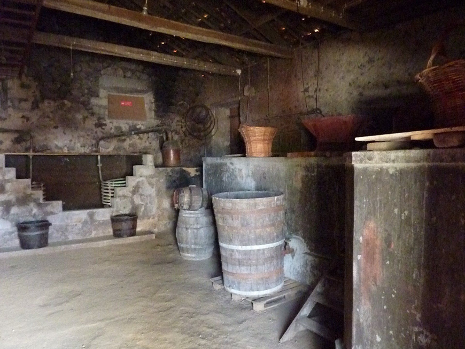 Interieur van een oud stenen gebouw met houten vaten, manden en een stenen oven.